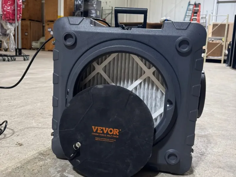 Portable air scrubber with a black circular cover labeled "VEVOR" removed, showing the filter inside.