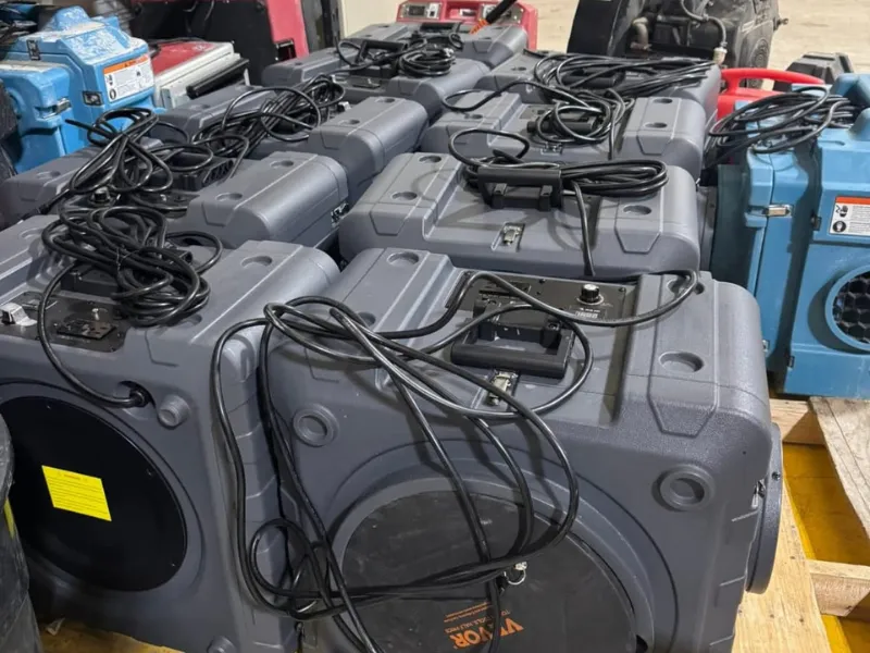 Stack of gray portable speakers with coiled black cables on top.